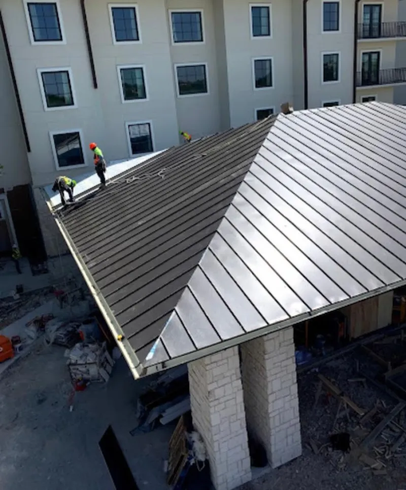 Crew installing standing seam metal roof panels on a commercial project in Midland